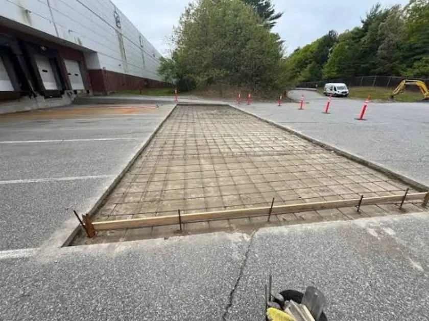 Long rectangular trailer apron excavation with a reinforcement grid before concrete placement